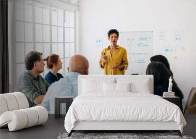 Black project manager having a meeting with her team in a boardroom Wall mural