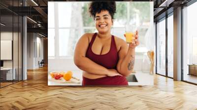 Body positive woman drinking fruit juice at home Wall mural