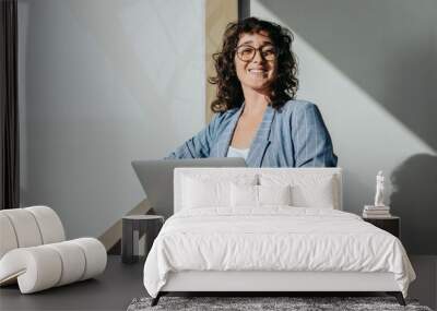 Cheerful businesswoman standing with a laptop on a balcony Wall mural