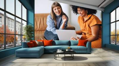 Cheerful young businesswomen using a laptop together in an office Wall mural