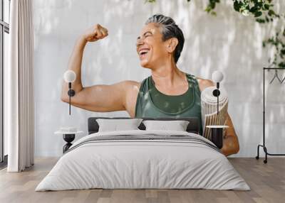 Elderly woman celebrates her fitness achievements by flaunting her bicep outdoors Wall mural