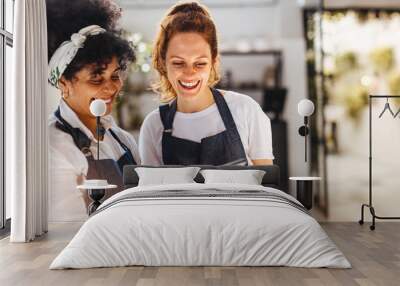 Female restaurant employees using a mobile app on a tablet for restaurant management Wall mural