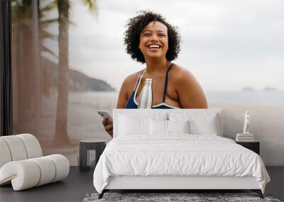 Fitness woman takes a refreshing break with her smartphone on beach promenade Wall mural