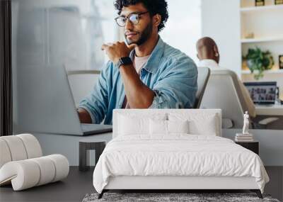 Focused young man working at laptop in bright office Wall mural