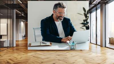 Happy bearded businessman working happily on laptop in a bright office Wall mural