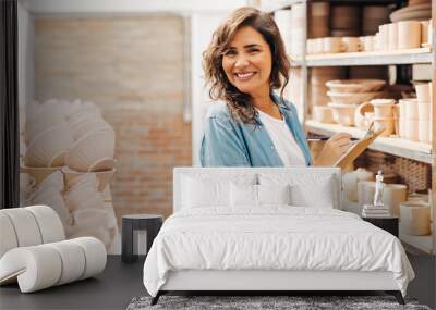 Happy young ceramist stocktaking in her shop Wall mural