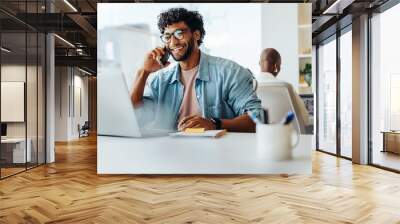 Happy young entrepreneur speaking on smartphone at modern office workplace Wall mural