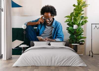 Mature man smiling and reading a message from his mobile phone at home Wall mural