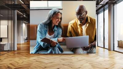 Modern team collaboration with mature black man and woman sitting, discussing over a laptop Wall mural