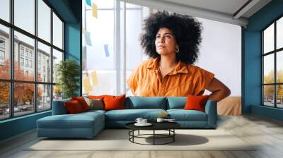 Pensive young businesswoman standing next to a glass wall Wall mural