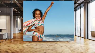 Proud young girl having fun at the beach with a towel cape on a sunny day Wall mural