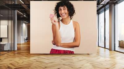 Responsible young woman holding a latex condom Wall mural