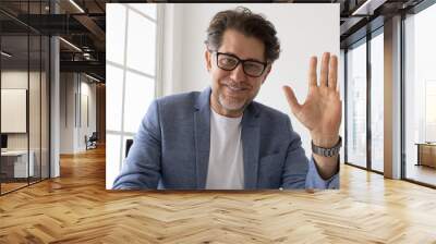 Senior business man waving to his colleagues on a video call Wall mural