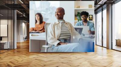 Successful entrepreneur smiling and thinking in creative office setting Wall mural