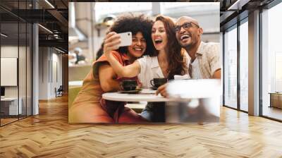 Three happy friends having fun and creating memories with selfies Wall mural