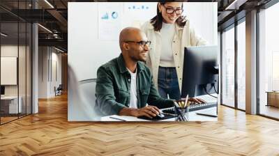 Web developers using a computer together in an office Wall mural