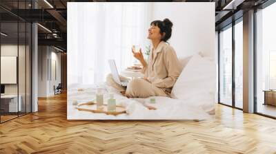 Woman doing video call on laptop holding wine glass Wall mural