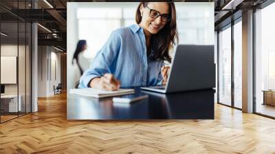 Woman making notes during an online business meeting in an office Wall mural