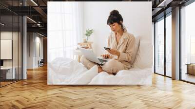 Woman making online payment using credit card Wall mural