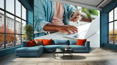 Young businessman using smartphone and laptop at the office Wall mural