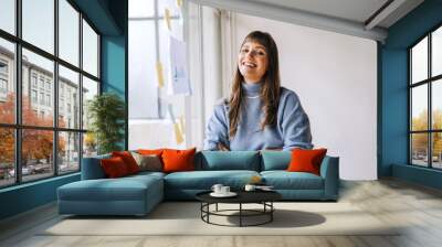 Young businesswoman smiling at the camera in a creative office Wall mural