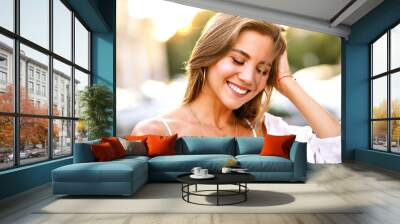 Sensual young woman with amazing smile posing on the street at sunset light, casual stylish out and golden accessories, natural pure beauty. Wall mural