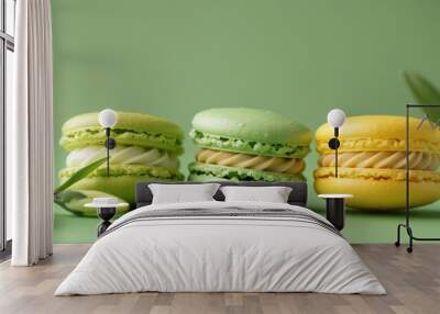 Three macaroon cookies in green and yellow with a floral bud on a green backdrop Wall mural