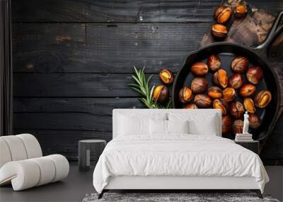 Top view of cast iron pan with roasted chestnuts on dark wooden background with rosemary and space for text Wall mural