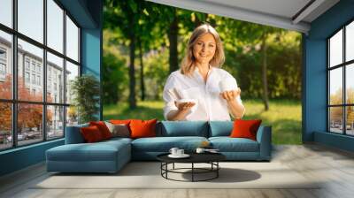 Portrait of an adult confident woman holding a white open jar of body cream in her hand. Wall mural