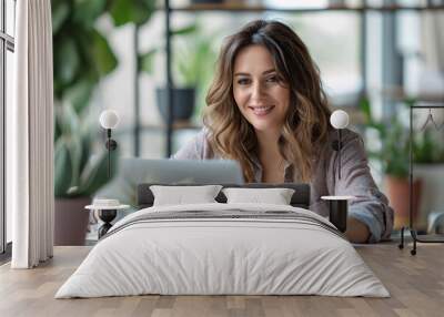 Young business woman teleworking and using a laptop on a table at home to search for information, perform tasks, shop online, etc.... Wall mural