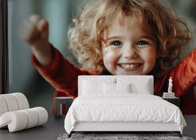 A child with a radiant smile and curly hair, wearing a red outfit, beams joyfully in an indoor setting, embodying the innocence and happiness of youth. Wall mural