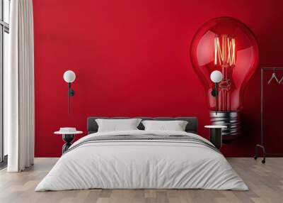 A close-up capture of a glowing red light bulb positioned against a dark red background, bringing focus to its filament and highlighting the play of light and shadow. Wall mural