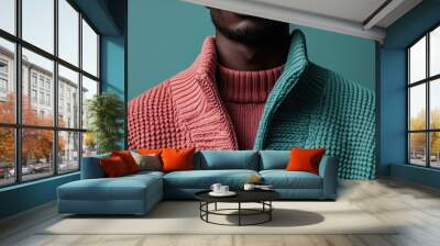 A person is seen wearing a dual-tone knit sweater with pink and blue sections, set against a colored backdrop, displaying a cozy yet trendy fashion sense perfect for cooler seasons. Wall mural