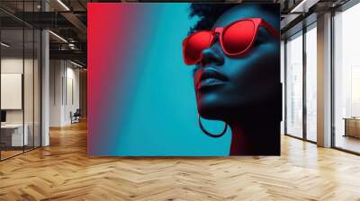 A stylish individual wearing sunglasses poses with vibrant red and blue artistic lighting, conveying a sense of modernity, sophistication, and contemporary fashion. Wall mural