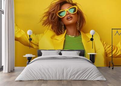 A stylish model wearing a vibrant yellow blazer and sunglasses, embodying a bold fashion statement with a confident pose against a matching yellow backdrop. Wall mural