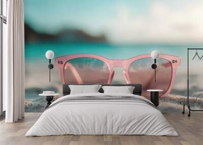 This image features pink sunglasses laying on a sandy beach with a vibrant ocean and sky in the background, highlighting a serene and relaxing vacation setting. Wall mural