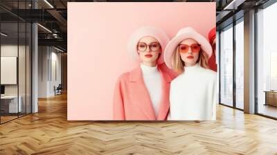 Trio of trendy women in coordinated pink high-fashion attire and hats, portraying a confident and stylish image against a neutral backdrop of timeless elegance. Wall mural