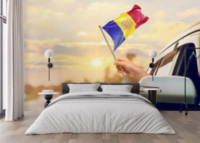 Waving the Andorra flag against the sunrise or sunset from a car driving along a country road. Holding the Andorra flag, traveling by car, on a weekend trip. Wall mural