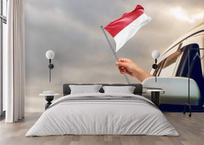 Waving the Monaco flag against the sunrise or sunset from a car driving along a country road. Holding the Monaco flag, traveling by car, on a weekend trip. Wall mural