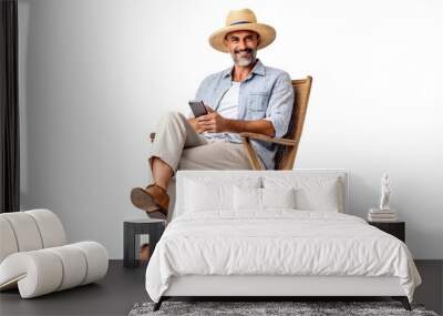 Mature male tourist sitting on a beach chair with a smartphone. an old man wearing beach clothes. Isolated on white background. Generated AI  Wall mural