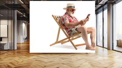 Mature male tourist sitting on a beach chair with a smartphone. an old man wearing beach clothes. Isolated on white background Wall mural