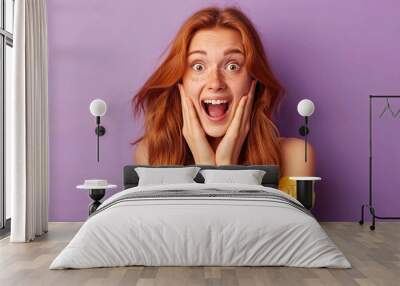 Portrait of an excited young ginger young woman isolated on purple background  Wall mural