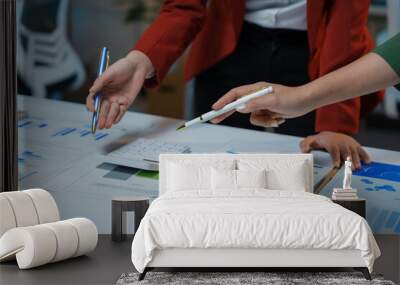 Two businesswomen pointing at financial data with pens, collaborating on a project and discussing business strategy Wall mural