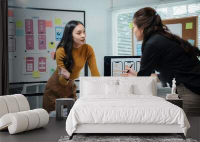 Two female uiux designers discussing over new mobile application design project in modern office Wall mural