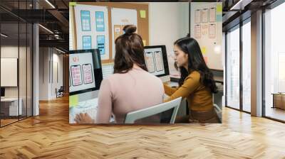 Two female web designers working together on a ux ui design project for a mobile application Wall mural