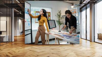 Two young asian web designers are discussing user interface design for mobile application in the office Wall mural