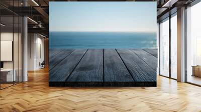 Dark wooden tabletop with a softly blurred seascape and clear blue sky in the background High resolution image Wall mural