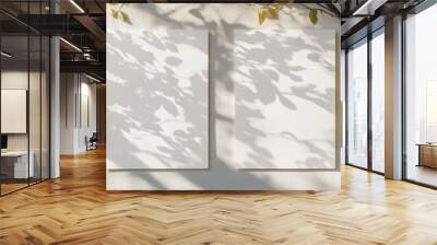 Two blank white vertical poster mockups with soft shadows of linden tree leaves against a neutral light gray concrete wall Flat lay perspective Wall mural