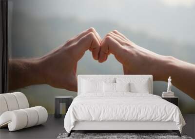 Heart-shaped hands gesture symbolizing love and connection against nature background. Wall mural