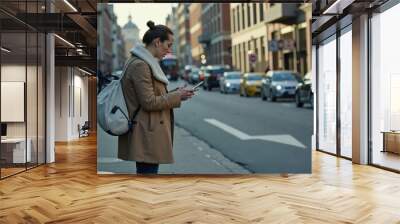 Urban commuter woman in stylish coat using smartphone on busy city street in autumn. Wall mural